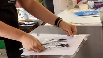 Person zieht Bild auf Papier nach, drinnen.