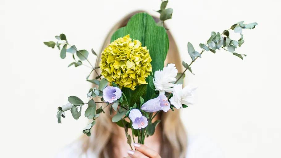 Person hält Blumenstrauß vor das Gesicht.