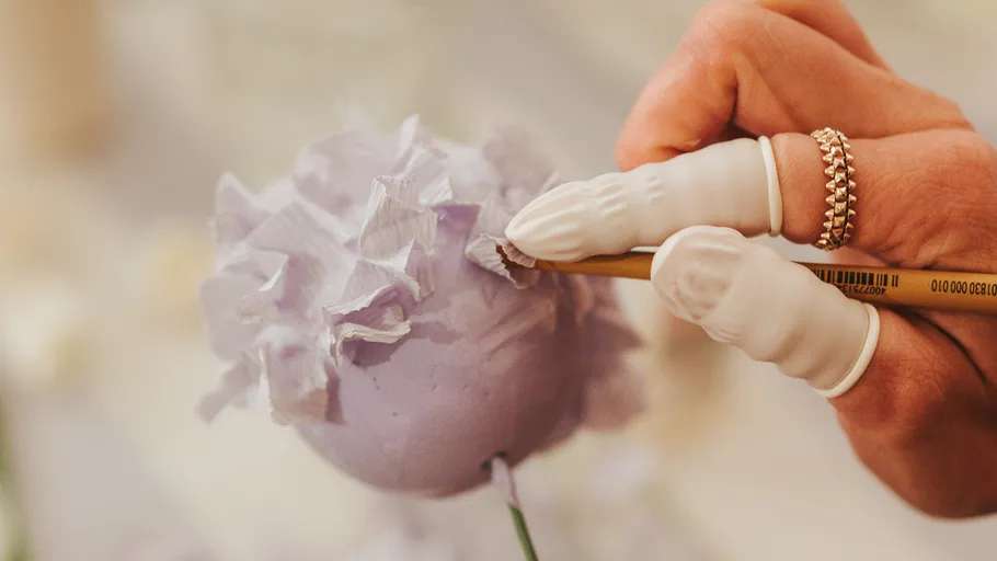 Hand crafting purple flower decoration.