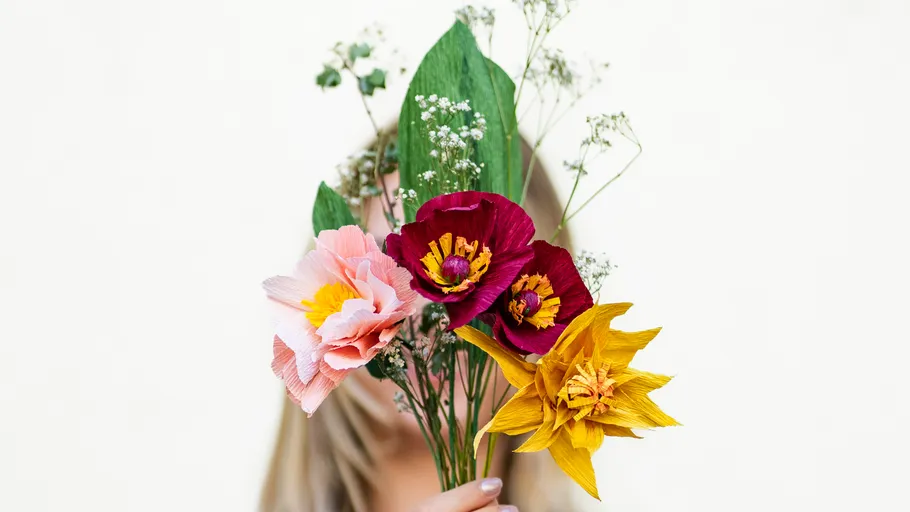 Person hält bunten Papierblumenstrauß.