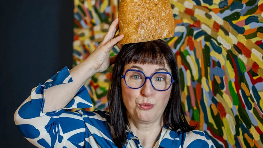 Person balanciert Brot auf Kopf, bunter Hintergrund.