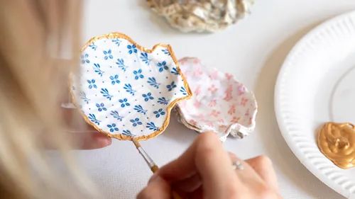 Person painting decorative shells on table.