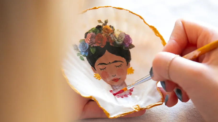 Person paints portrait inside a seashell.