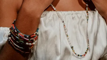 Person wearing colorful bead bracelets and necklace.