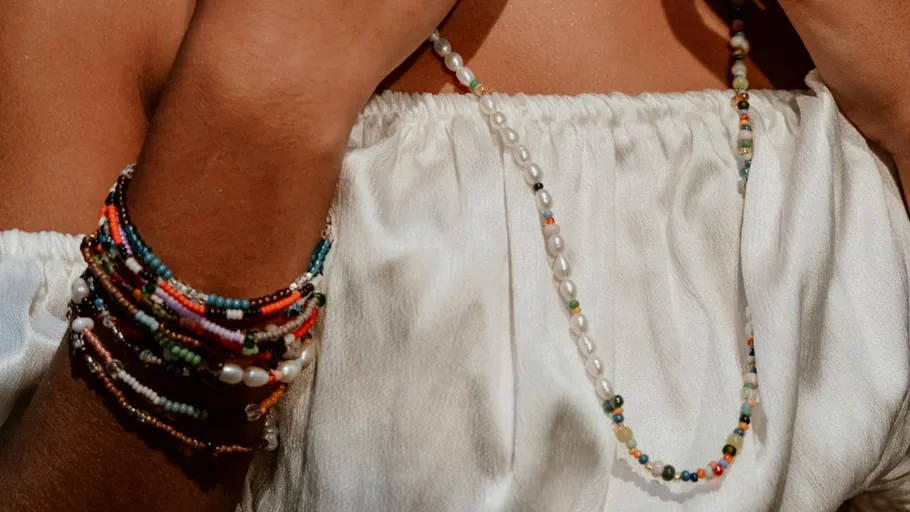 Person wearing colorful bead bracelets and necklace.