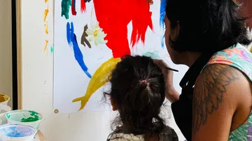 Woman and child painting colorful wall art.