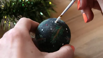 Hand painting ornament in festive setting.
