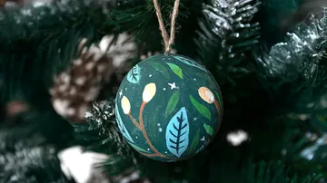 Painted ornament hanging on Christmas tree.