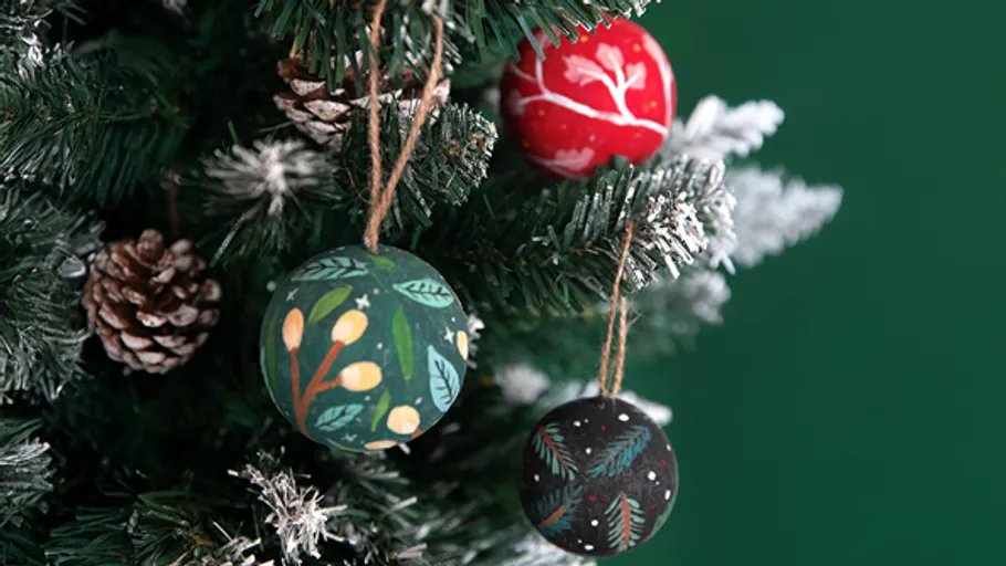Dekorierte Kugeln hängen an einem Weihnachtsbaum.