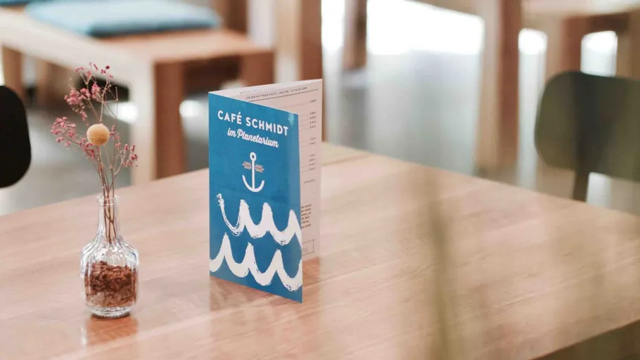 Menu on a cafe table with vase.