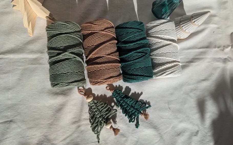 Vier Garnrollen und kleine Bäume auf Stoff.