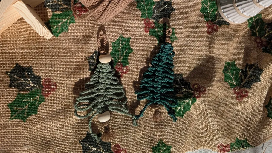 Two macramé Christmas trees on festive cloth.