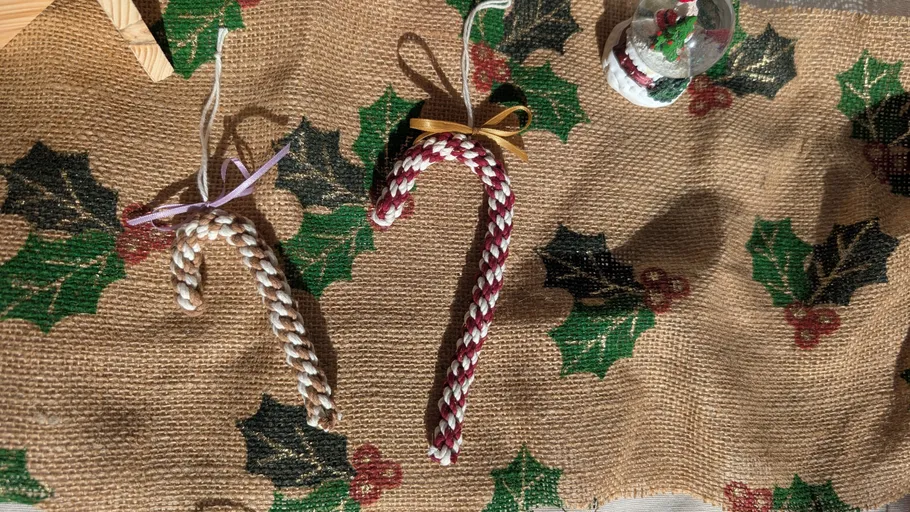Two braided candy canes on burlap with holly design.
