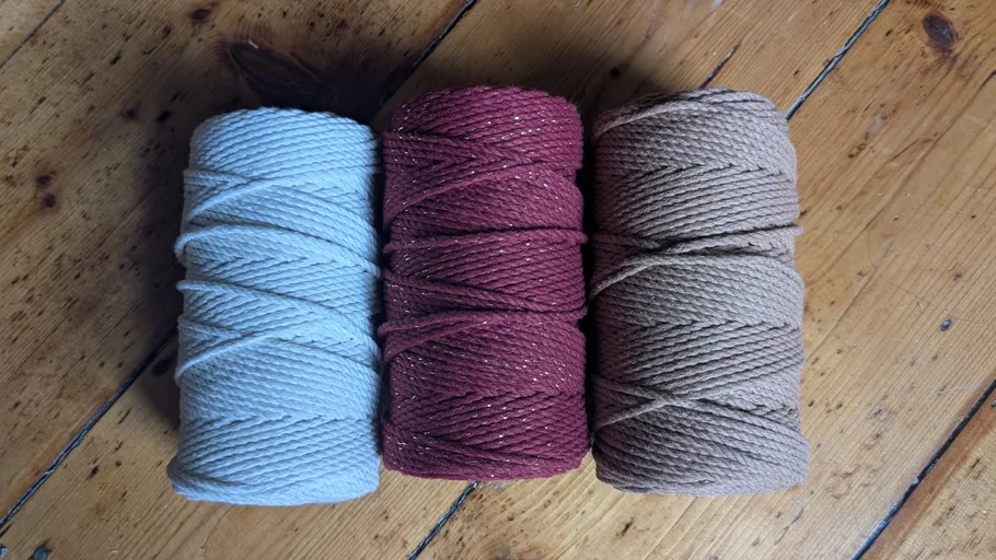 Three rolls of yarn on wooden floor.