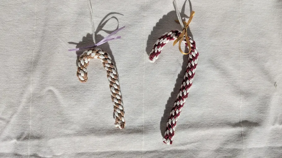 Two braided candy canes hanging on fabric.
