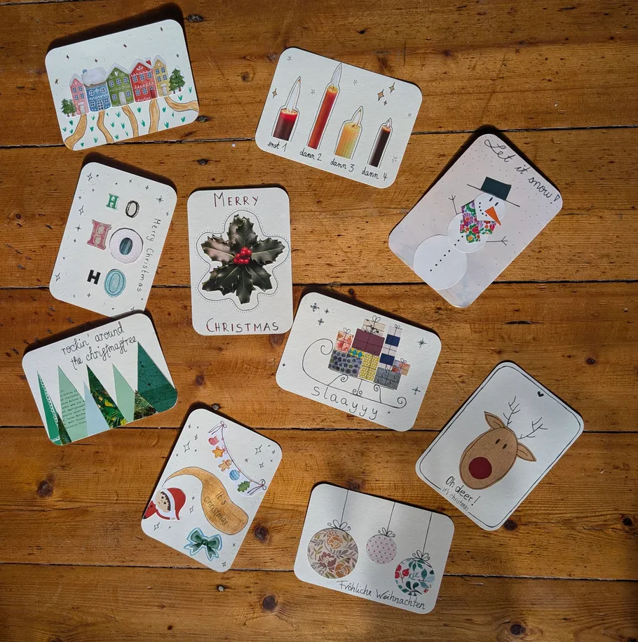 Neun handgemachte Weihnachtskarten auf Holztisch.