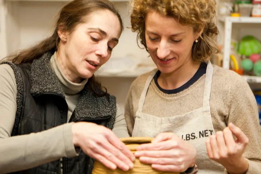 Zwei Frauen arbeiten an einem Töpferprojekt drinnen.