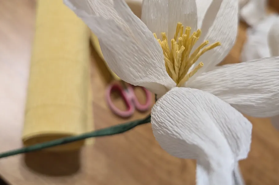 Papierblumenbasteln mit Schere auf Tisch.
