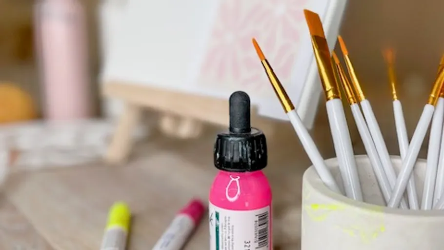 Art supplies: brushes, paint, markers on table.