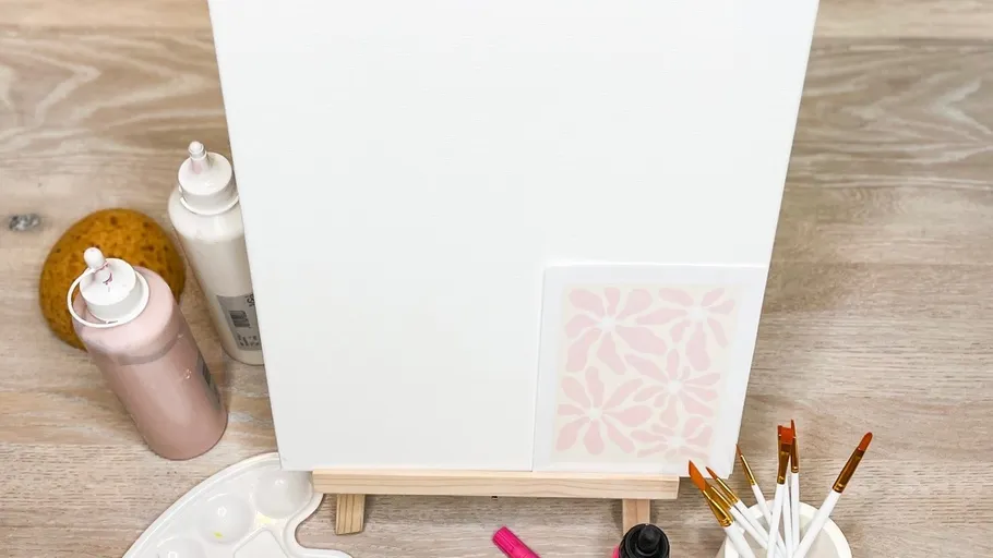 Blank canvas on easel with paint supplies.