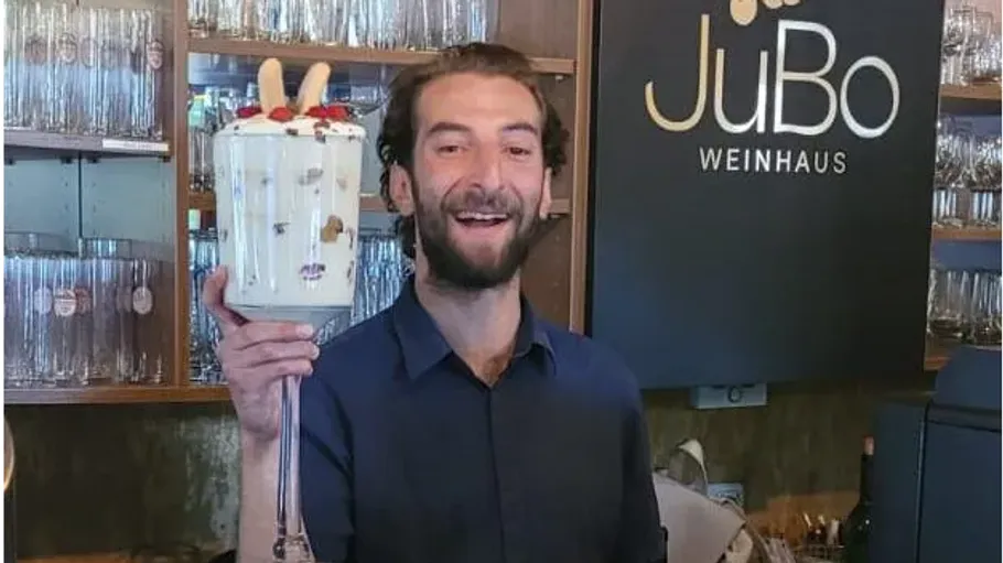 Person hält großes Dessertglas im Restaurant.