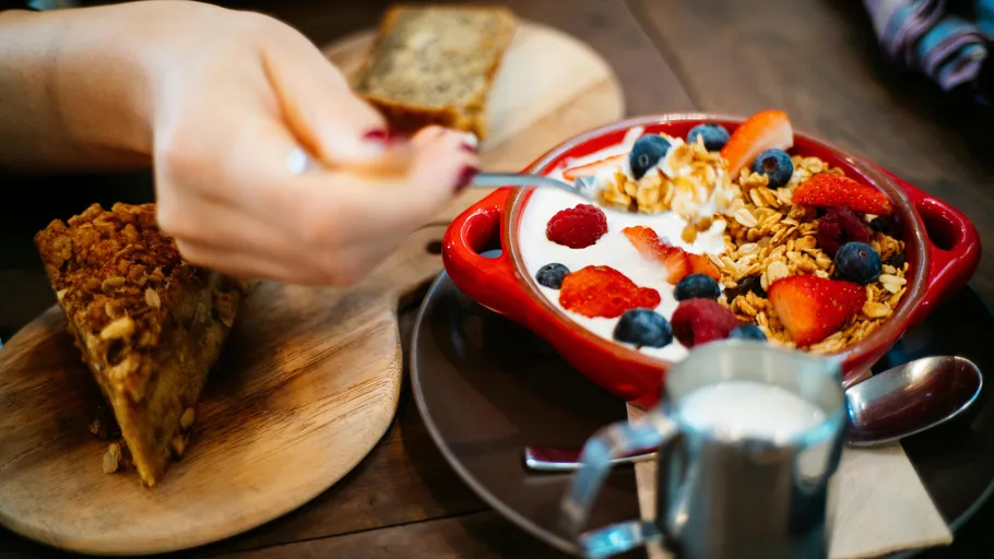 Person eating granola and berries breakfast.