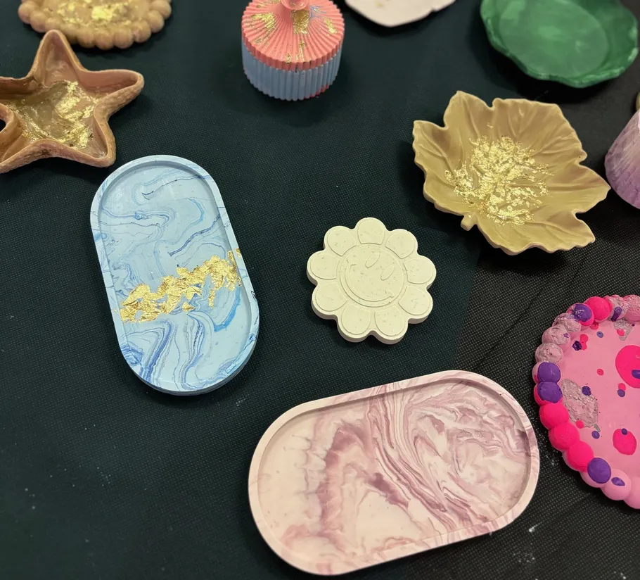 Colorful clay trays and decorations on black fabric.