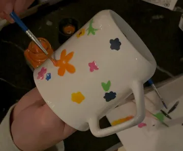 Hand painting colorful flowers on mug.