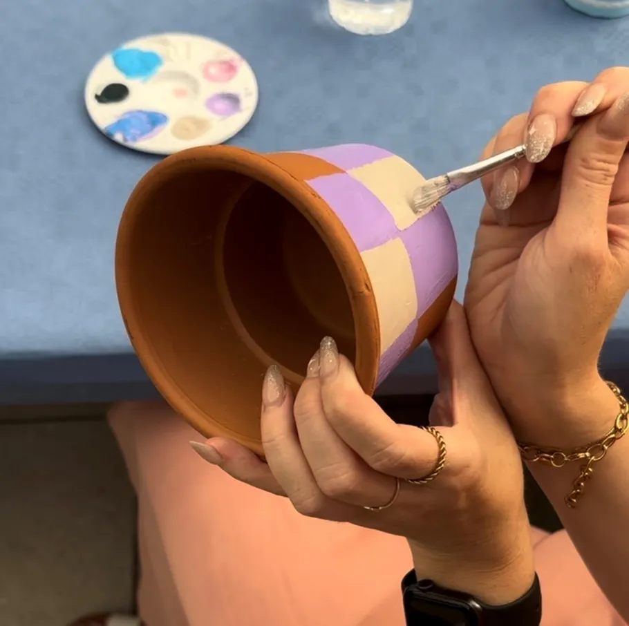 Hands painting pot with checkered pattern.