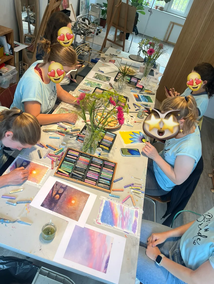 People creating pastel art at a table.