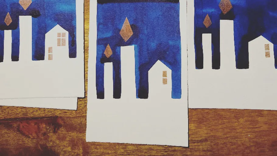 Abstract houses on blue background, wooden surface.