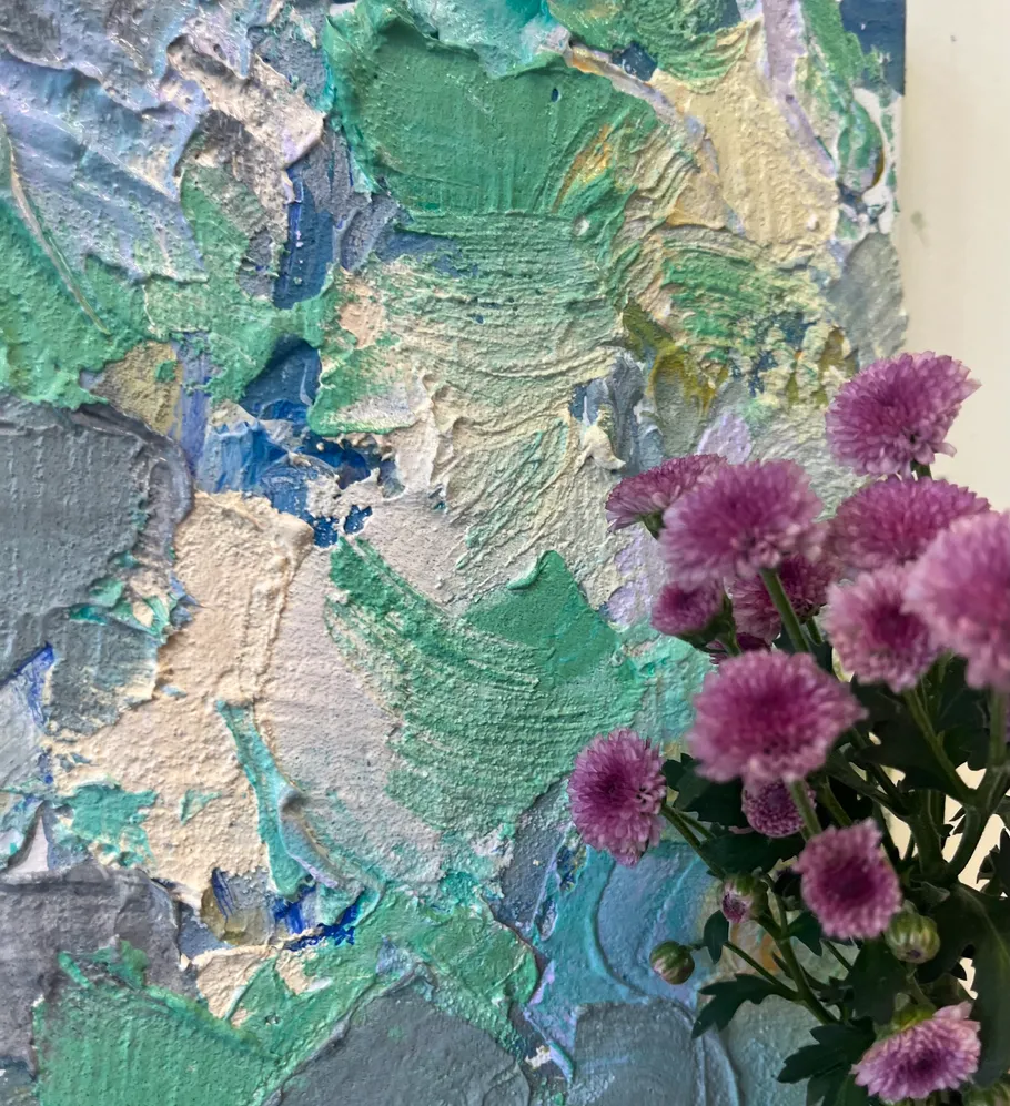 Pink flowers beside textured colorful painting.