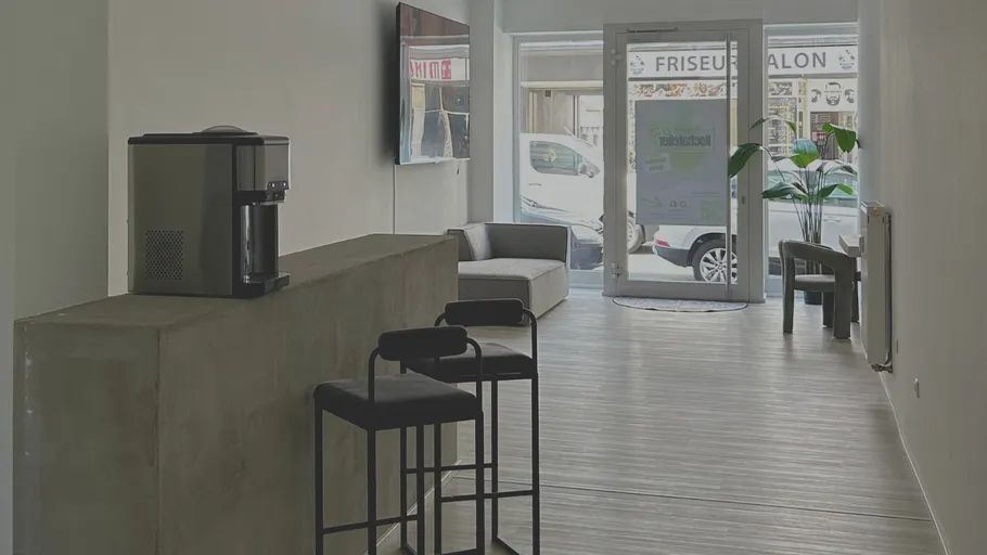 Modern kitchen showroom with seating and coffee machine.