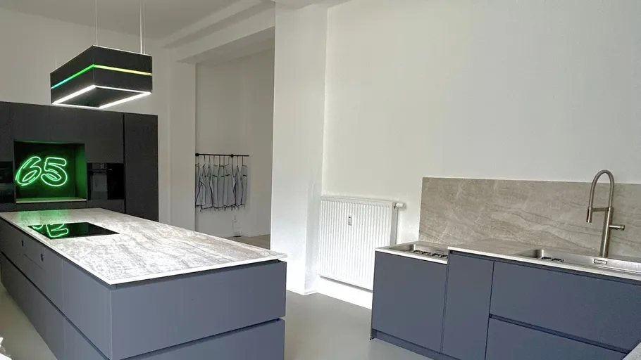 Moderne Küche mit grauen Schränken und Neonbeleuchtung.