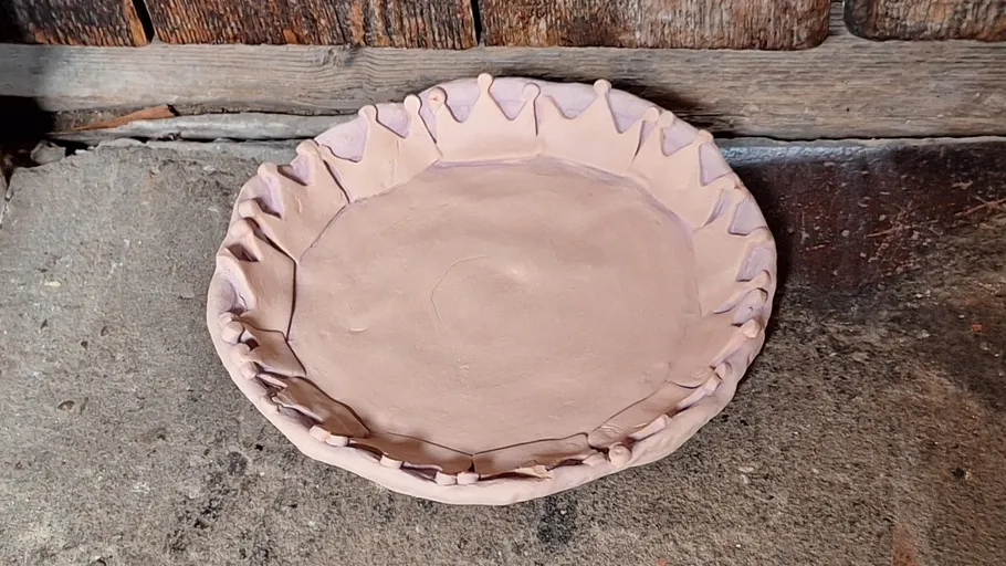 Clay bowl with decorative rim on stone surface.
