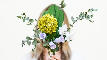 Person hält einen Blumenstrauß vor dem Gesicht.