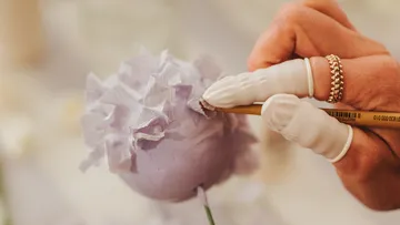 Hand fertigt sorgfältig Papierblütenblätter an.