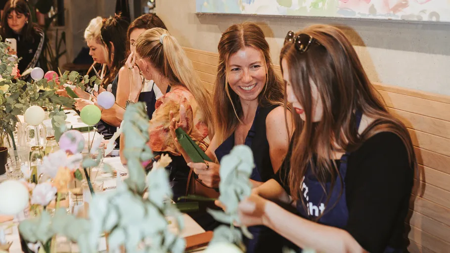 Frauen basteln an einem Tisch mit Blumen.