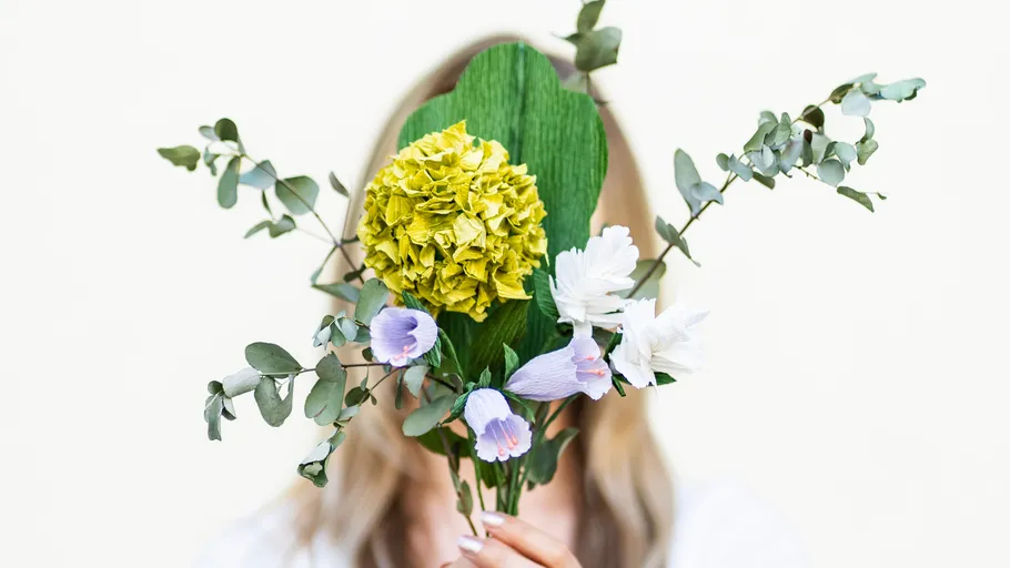 Person hält Blumen, Gesicht verdeckt.