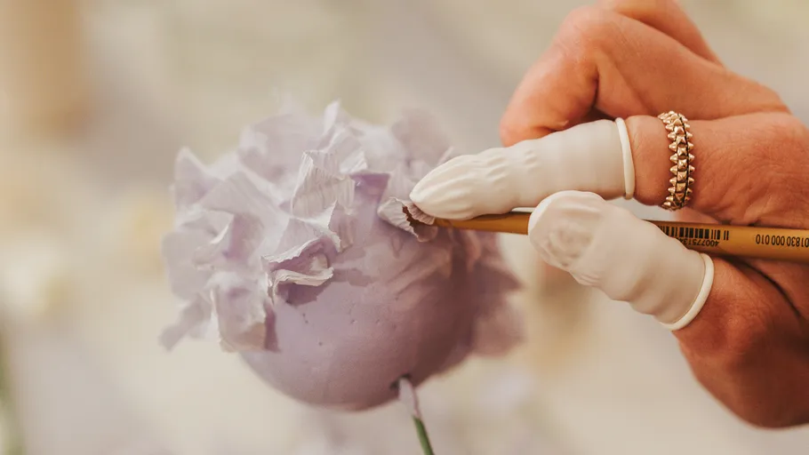Hand bastelt lila Blumenkugel.