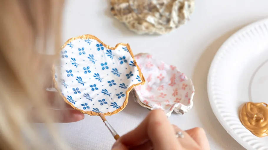 Hands painting decorative oyster shell.