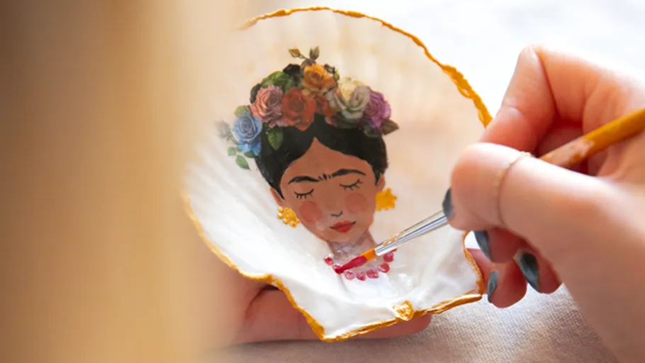 Hand painting a portrait on a shell.