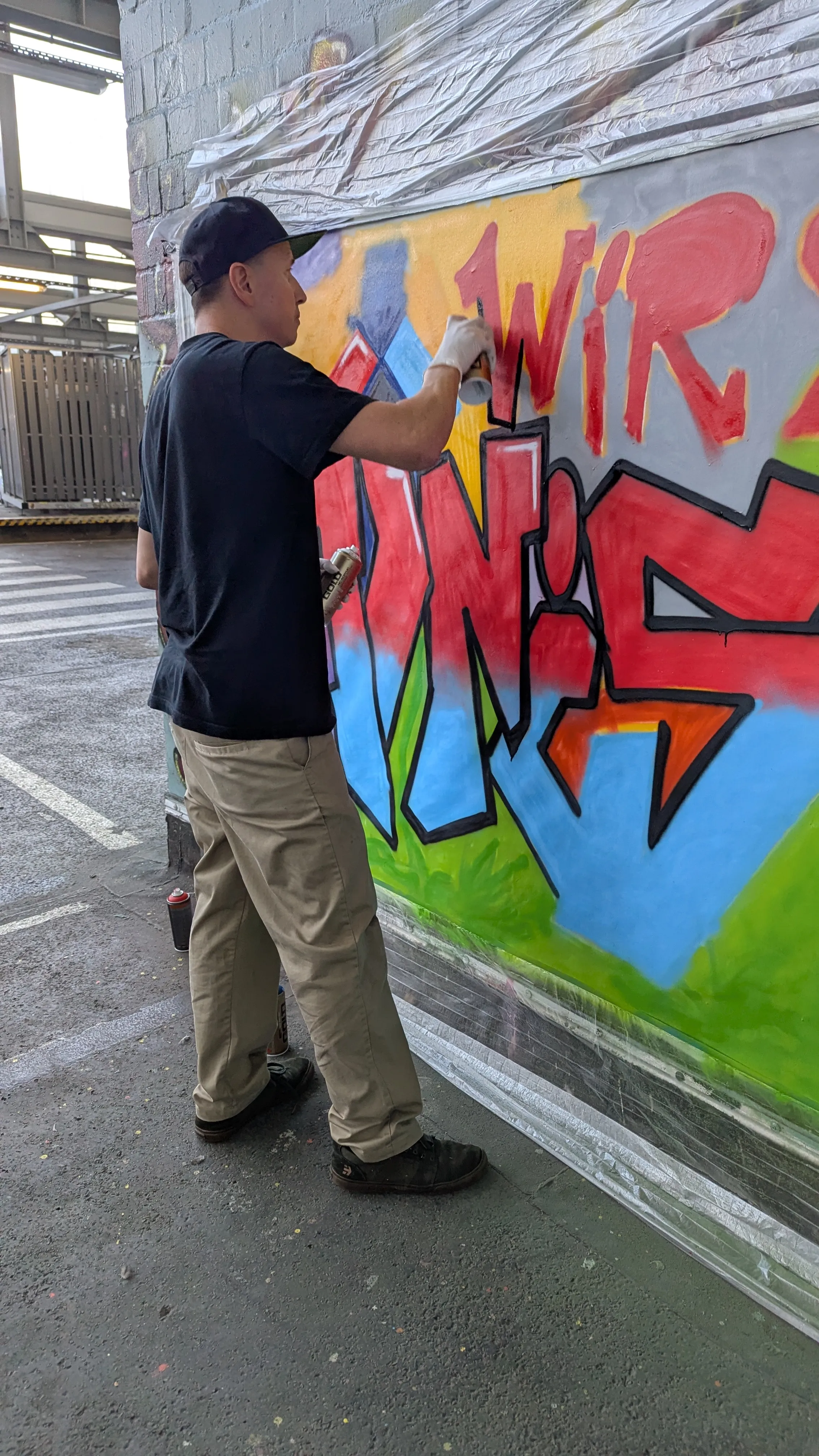 Künstler sprüht Graffiti an eine städtische Wand.