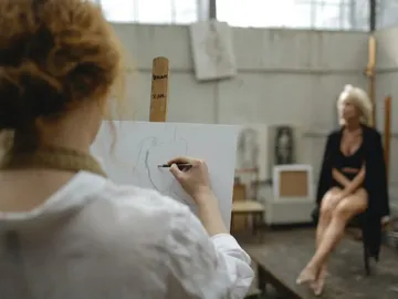 Künstlerin zeichnet eine Frau in einem Atelier.