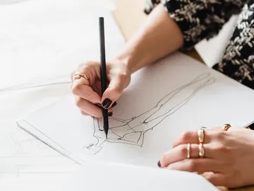 A hand draws a figure on paper.