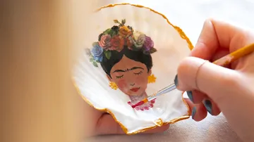 Person painting woman's portrait on a shell.