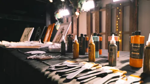 Art supplies on table with paintings nearby.