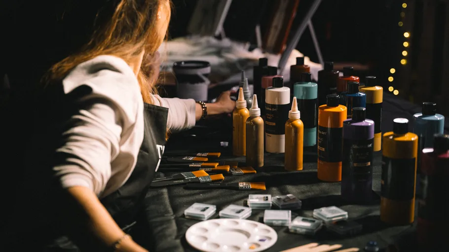 Person arranging paint bottles on a table.