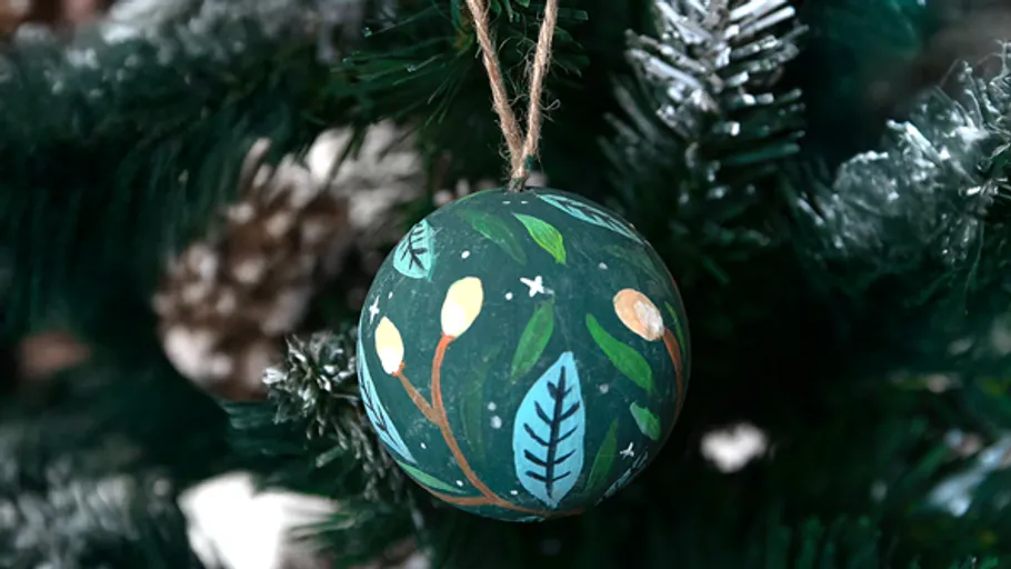 Bemalter Baumschmuck hängt an einem Weihnachtsbaum.
