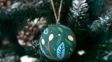Geschmückte Kugel hängt am Weihnachtsbaum.